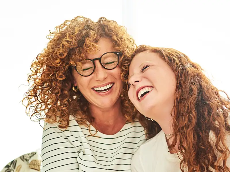 mother and teenage daughter smiling and laughing together