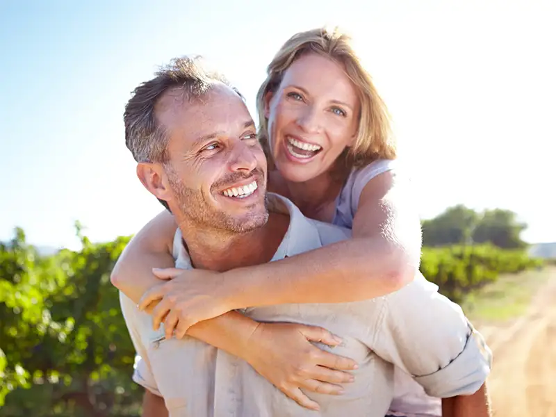 adult man and woman smiling together outdoors near trees