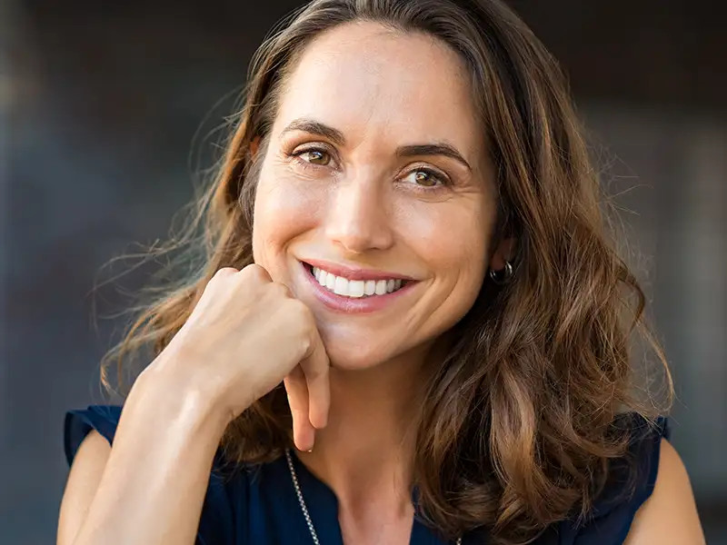 adult woman smiling with hand rested on chin