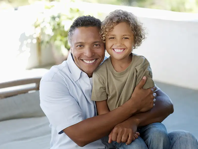 father smiling with son at home on back porch