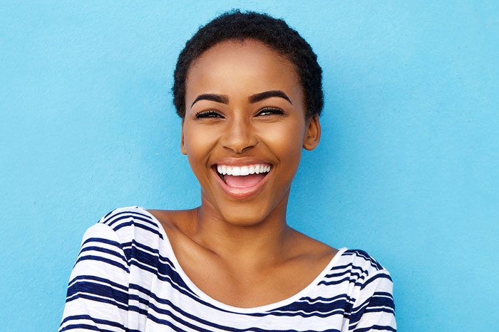 young woman smiling in front of blue wall