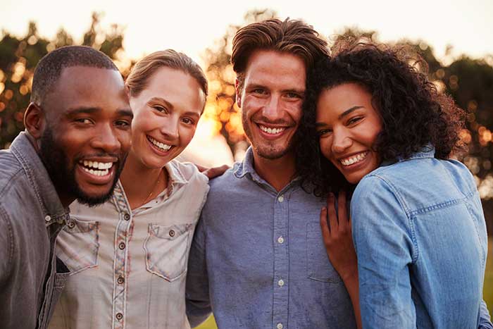 group of young adults smiling outdoors near trees