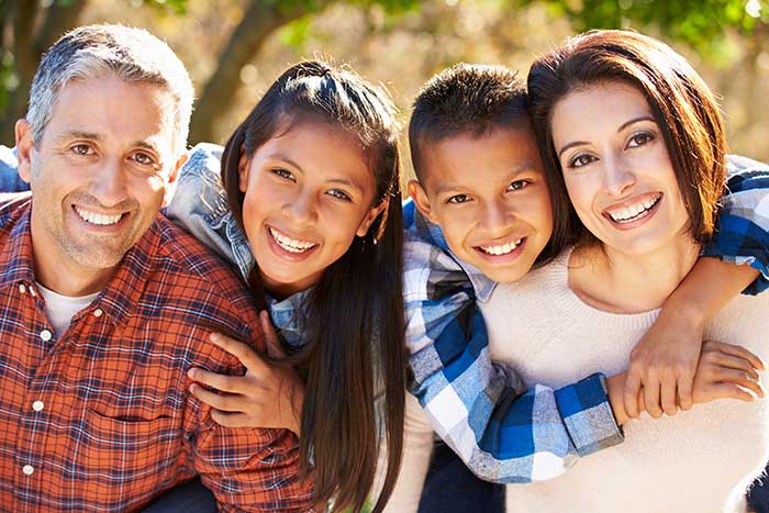 mother and father smiling with son and daughter outdoors