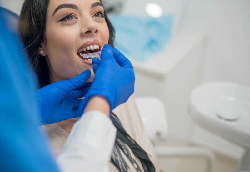 young woman having a mouthguard put in place by dentist