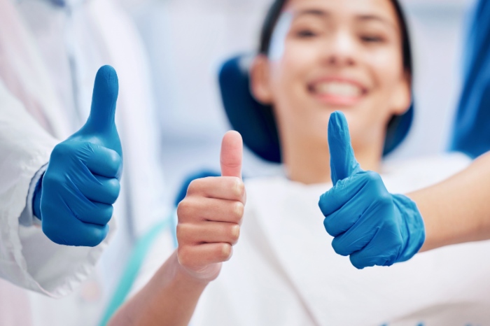 smiling woman and dentists giving thumbs up