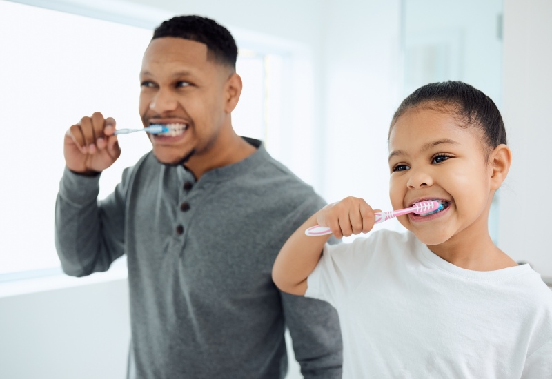 father and daughter brushing teeth together at home