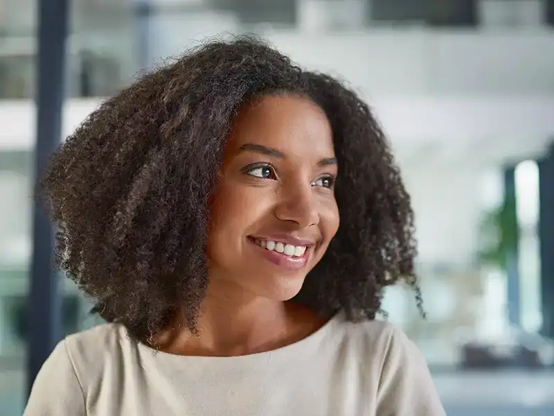 young woman smiling indoors and looking to side